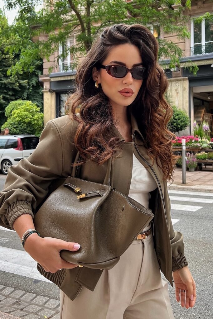 Olive Green Bomber Jacket + White Ribbed Tank + Beige Trousers + Olive Green Slouchy Bag + Gold Hoop Earrings