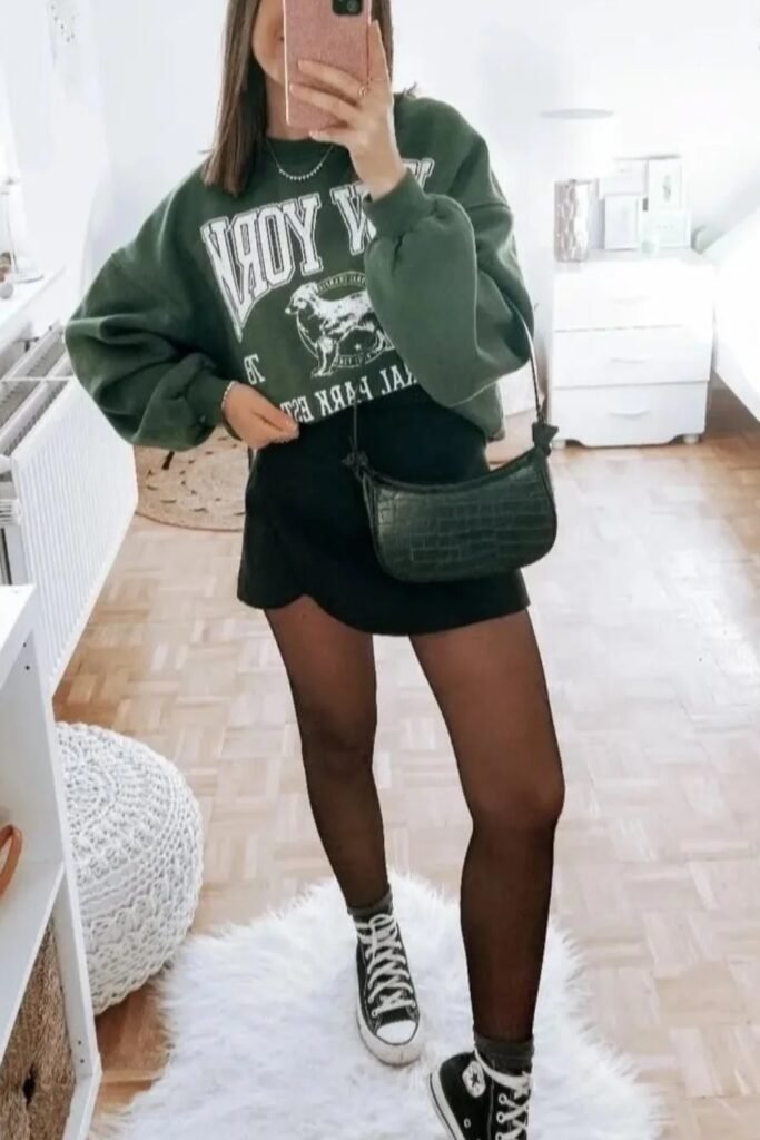 Oversized Green Graphic Sweatshirt + Black Mini Skirt + Black Tights + Black High-Top Converse Sneakers