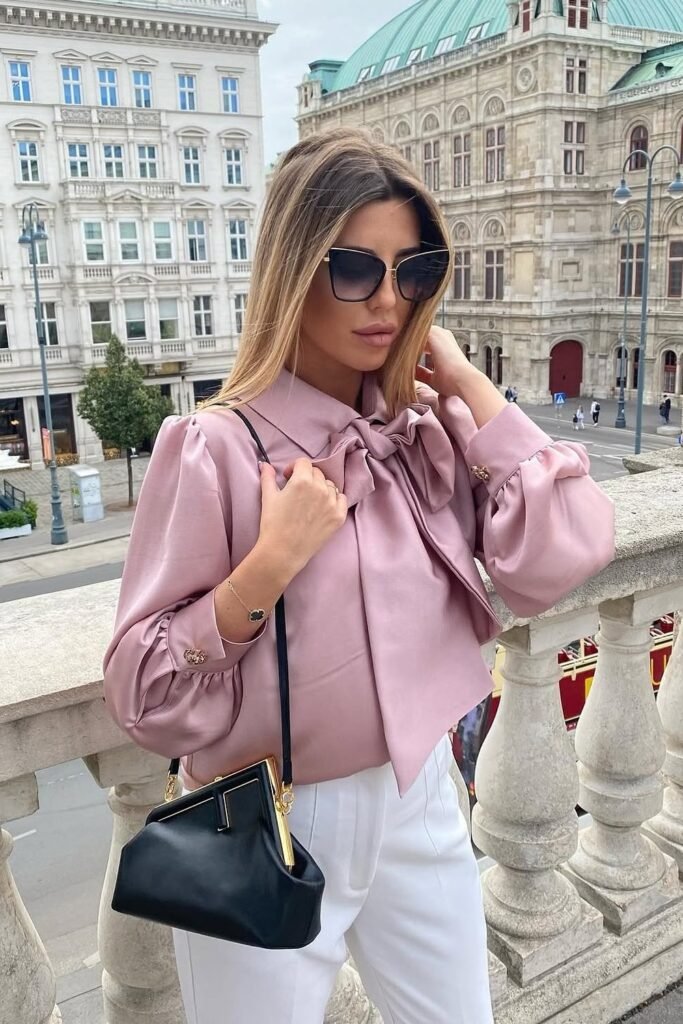 Pink Satin Bow Blouse with Puff Sleeves + White Wide-Leg Trousers + Black Frame Clutch Bag