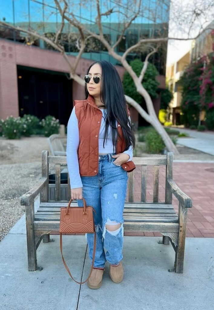 Rust Puffer Vest + White Long-Sleeve Top + Ripped Blue Jeans + Tan Slippers + Brown Handbag