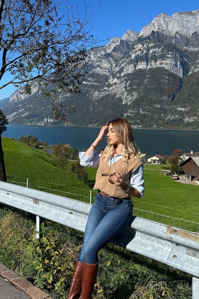 an Knit Vest + Light Blue Button-Down Shirt + Dark Wash Skinny Jeans + Brown Leather Knee-High Boots