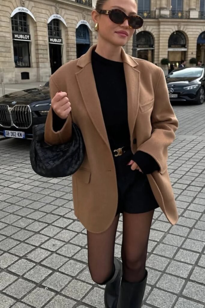 Tan Oversized Wool Blazer + Black Turtleneck + Black Shorts + Sheer Black Tights + Black Knee-High Boots + Black Woven Bag