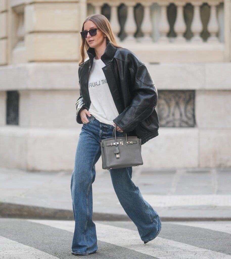 White T-shirt + Oversized Black Leather Bomber Jacket + Blue Flared Jeans + Grey Handbag