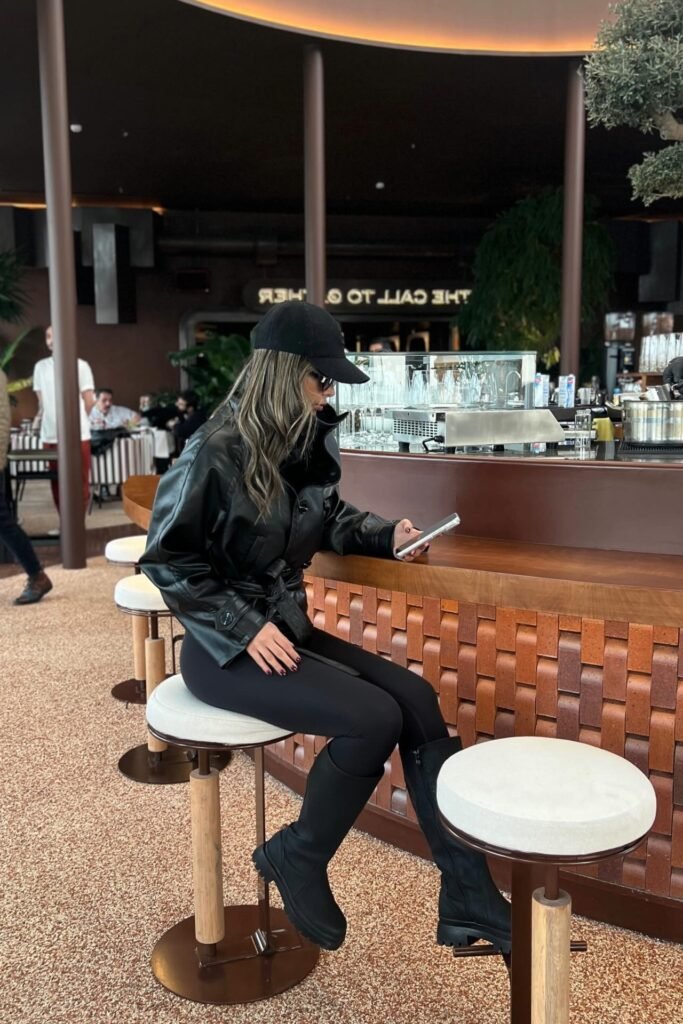 Black Baseball Cap + Belted Black Leather Jacket + Black Leggings + Black Knee-High Chunky Boots