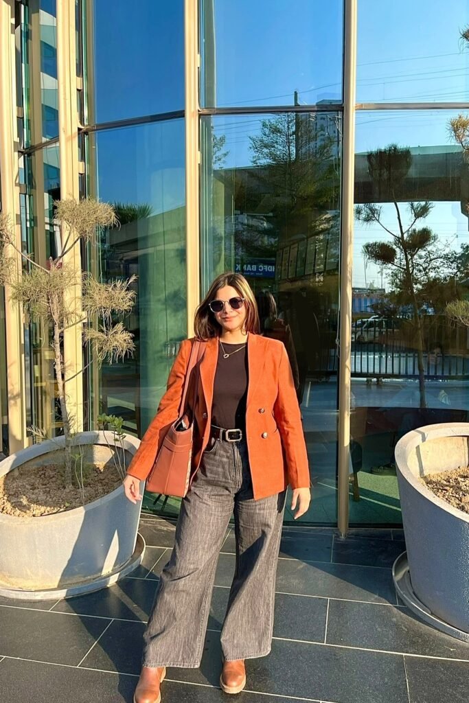 Black Crew-Neck Top + Burnt Orange Double-Breasted Blazer + Grey Wide-Leg Jeans + Brown Leather Boots