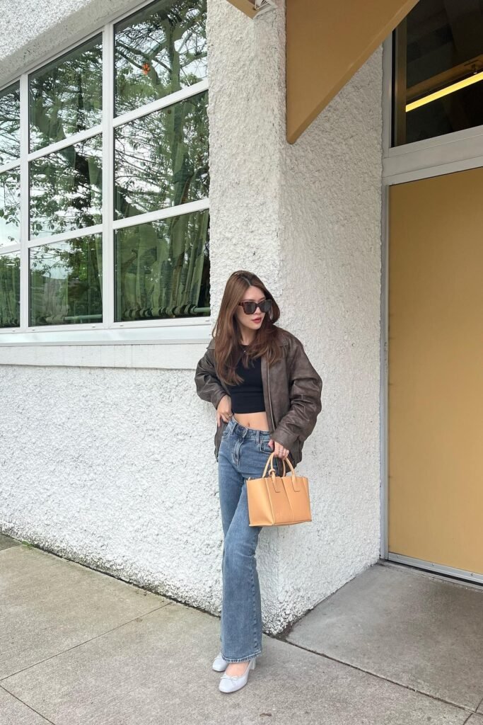 Black Crop Top + Distressed Brown Leather Bomber Jacket + Medium Wash Bootcut Jeans + Light Blue Ballet Flats