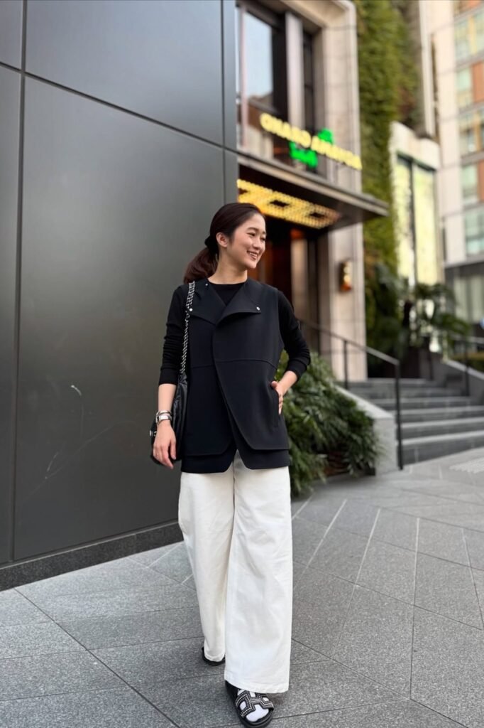 Black Long-Sleeve Top + Black Asymmetrical Vest + White Wide-Leg Trousers + Black Embellished Slides