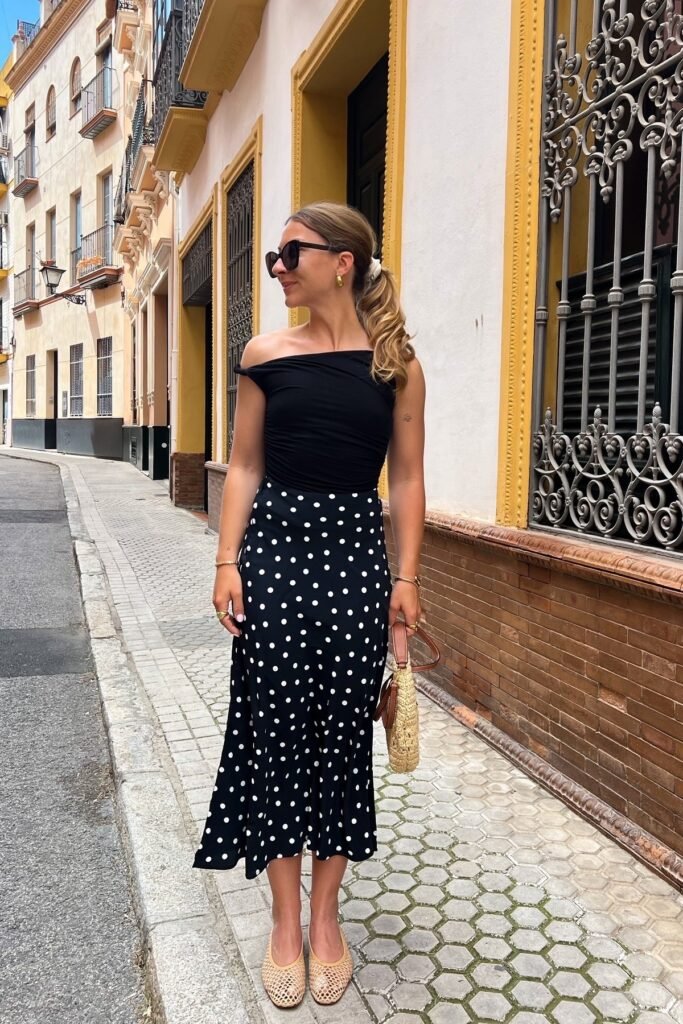 Black Off-the-Shoulder Bodysuit + Black and White Polka Dot Midi Skirt + Beige Woven Ballet Flats