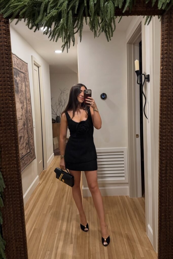 Black Sleeveless Mini Dress with Rosette Detail + Black Peep-Toe Heels + Black Handbag