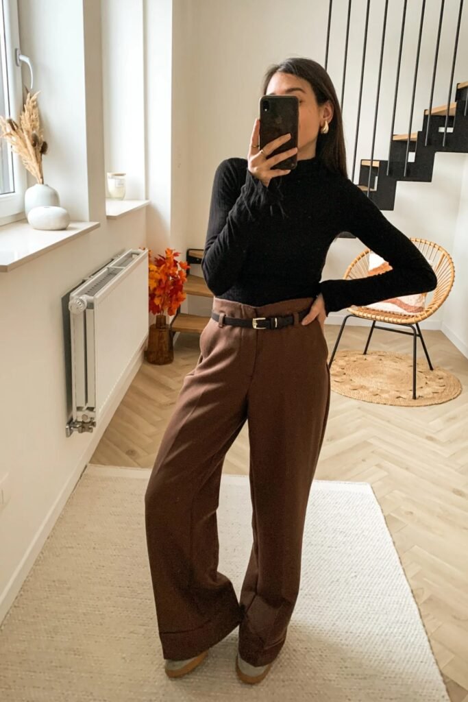 Black Turtleneck Top + High-Waisted Brown Trousers + Black Belt + Grey and White Sneakers