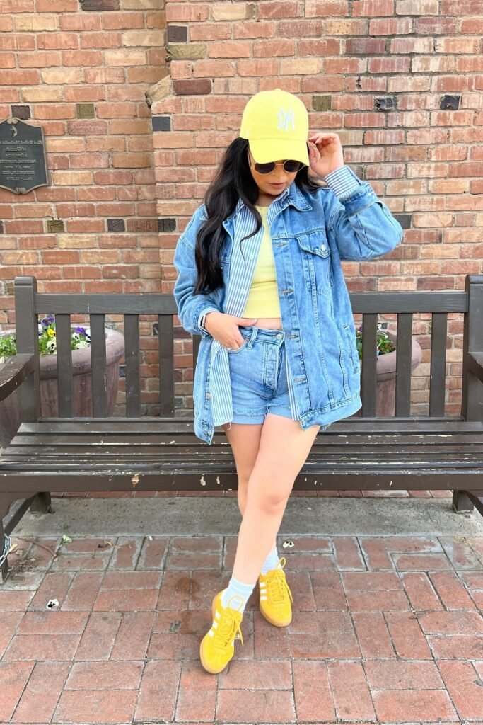 Oversized Denim Jacket + Blue Striped Button-Down + Yellow Crop Top + Denim Shorts + Yellow Sneakers