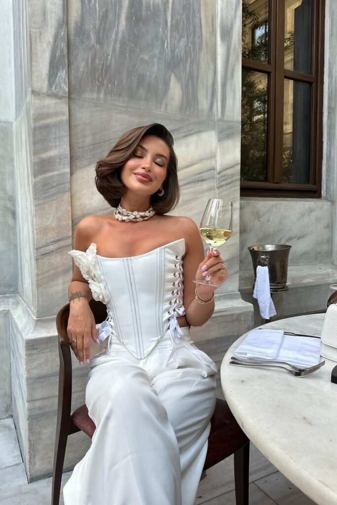 White Corset Top with Lace-Up Detail + White Wide-Leg Trousers + Pearl Necklace