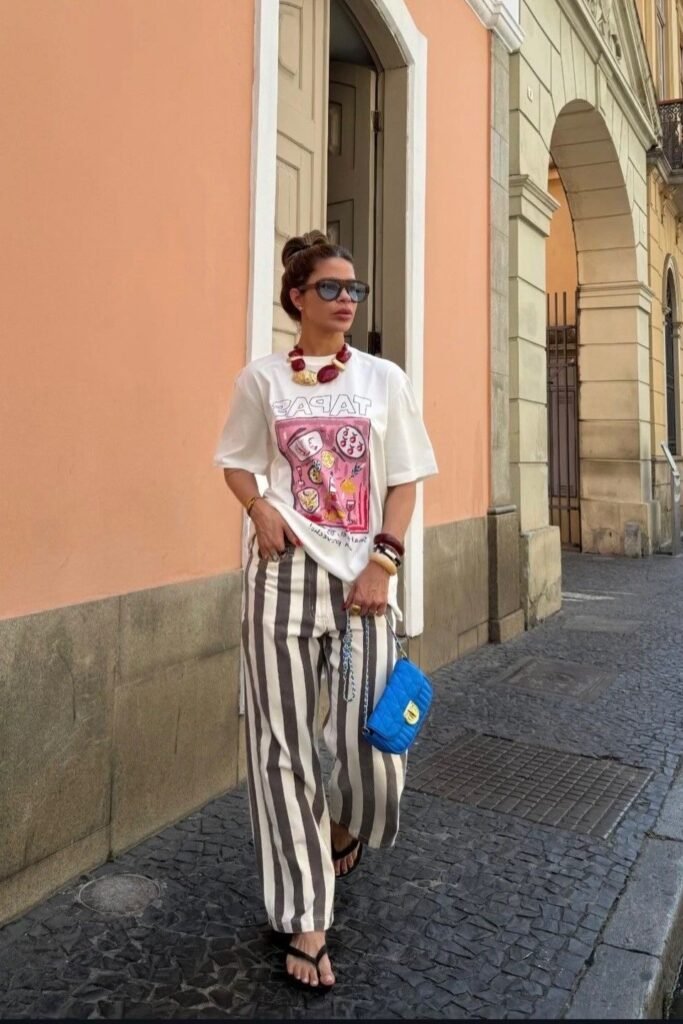 White Graphic T-Shirt + Brown and White Vertical Striped Wide-Leg Trousers + Black Flip-Flops