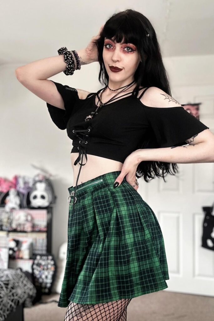 Black Cold-Shoulder Lace-Up Top + Green Plaid Pleated Skirt + Black Fishnet Tights