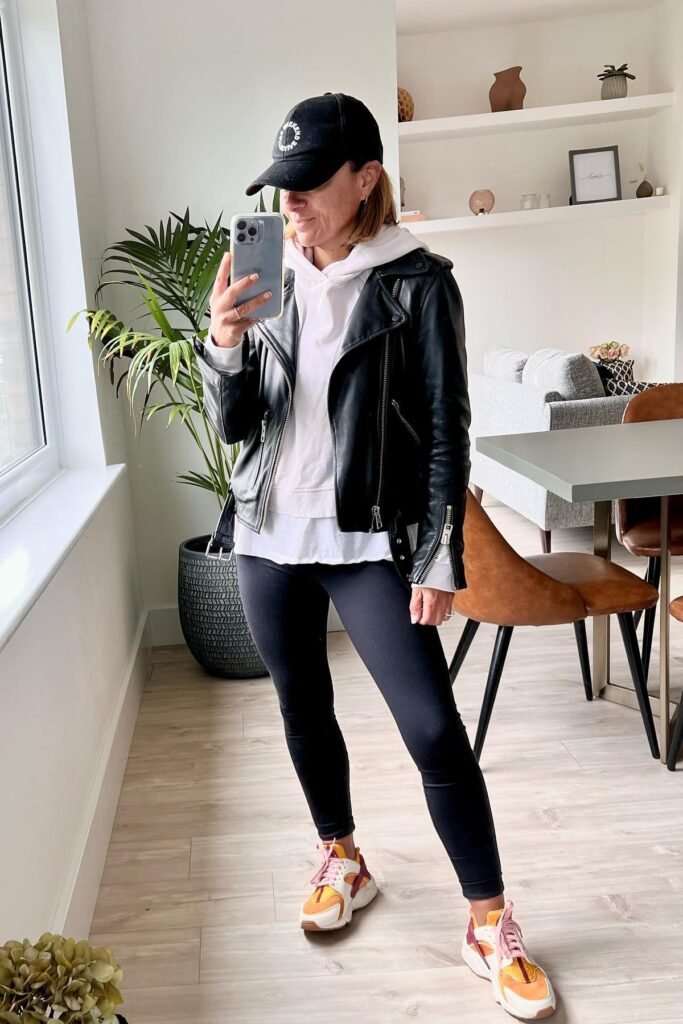 Black Leather Biker Jacket + White Hoodie + Black Leggings + Orange & White Sneakers