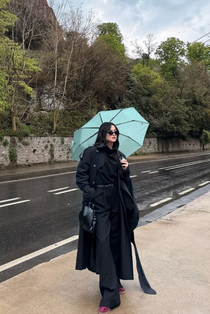 Black Maxi Trench Coat + Black High-Neck Top + Black Trousers + Burgundy Suede Sneakers