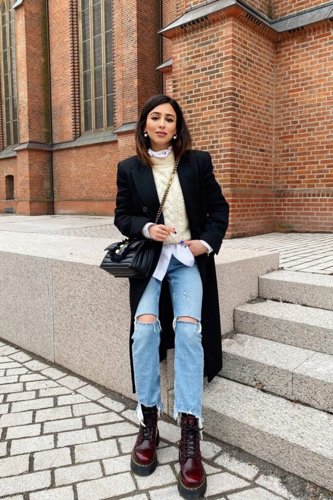 Black Overcoat + Cream Cable-Knit Sweater + Distressed Light Wash Jeans + Burgundy Combat Boots