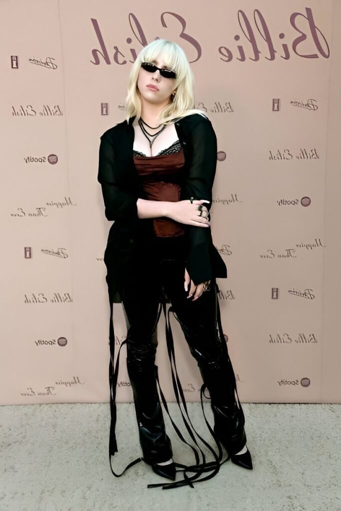 Black Sheer Button-Down + Burgundy Corset Top + Black Patent Leather Tassel Trousers + Pointed Black Heels + Rectangular Sunglasses