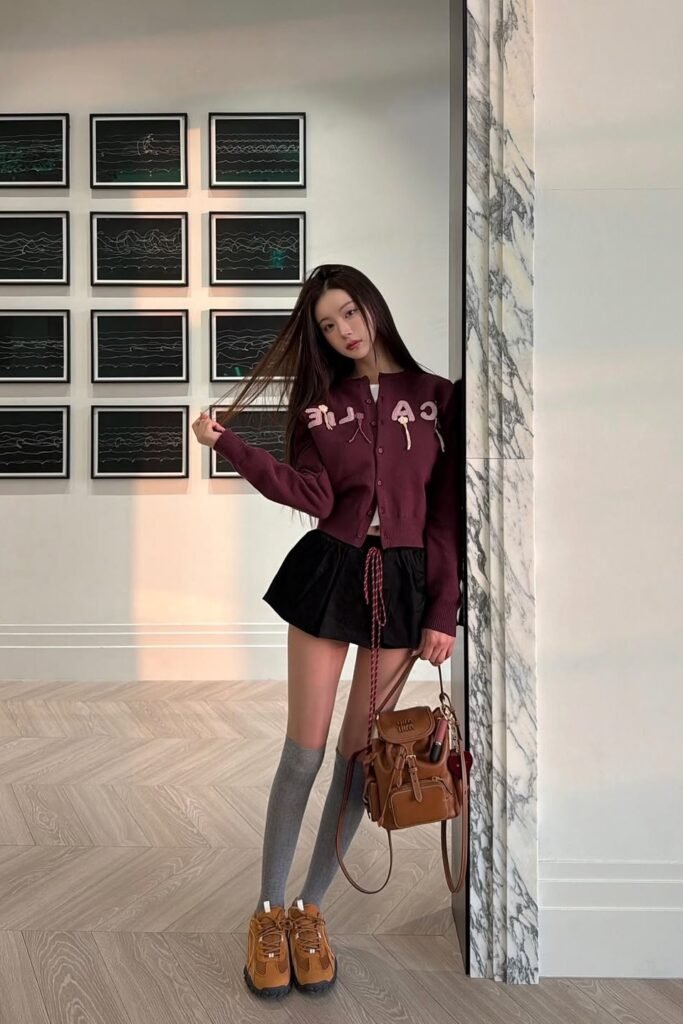 Burgundy Cardigan with Patches + Black Pleated Mini Skirt + Grey Knee-High Socks + Tan Athletic Sneakers