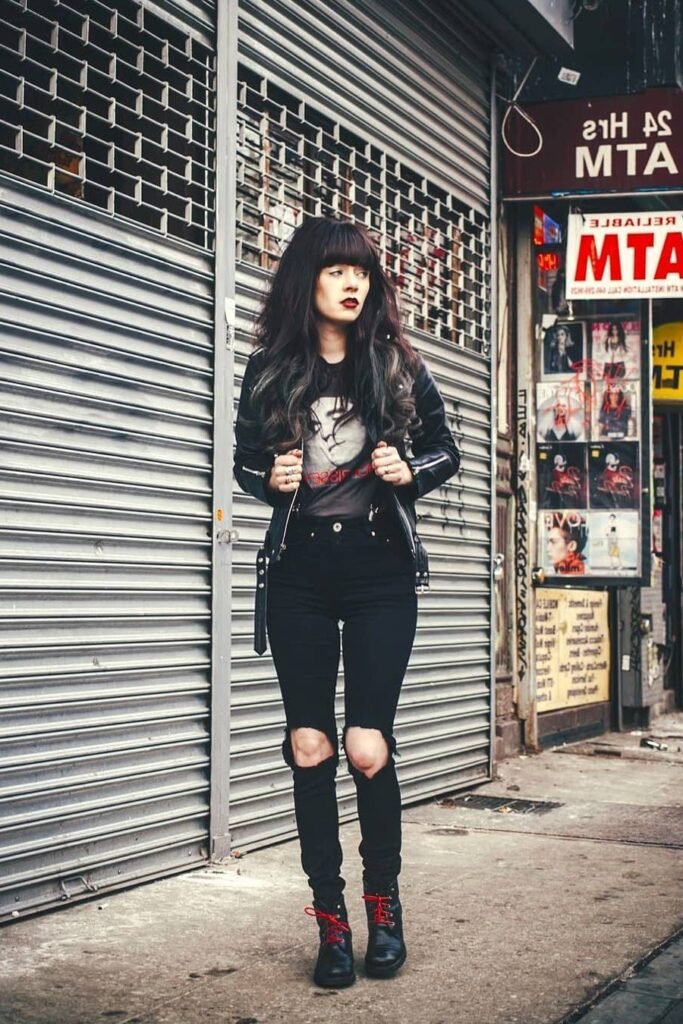 Leather Jacket over Graphic Tee + Ripped Black Skinny Jeans + Black Boots with Red Laces