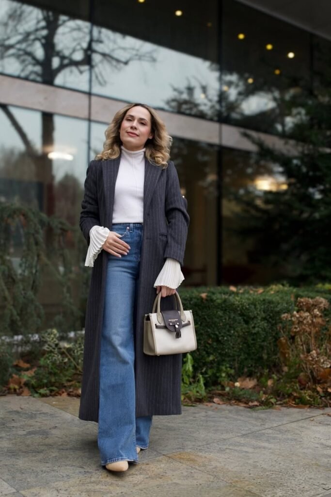 Long Charcoal Pinstripe Coat + White Mock-Neck Top + Blue Flared Jeans + Cream Pointed Heels