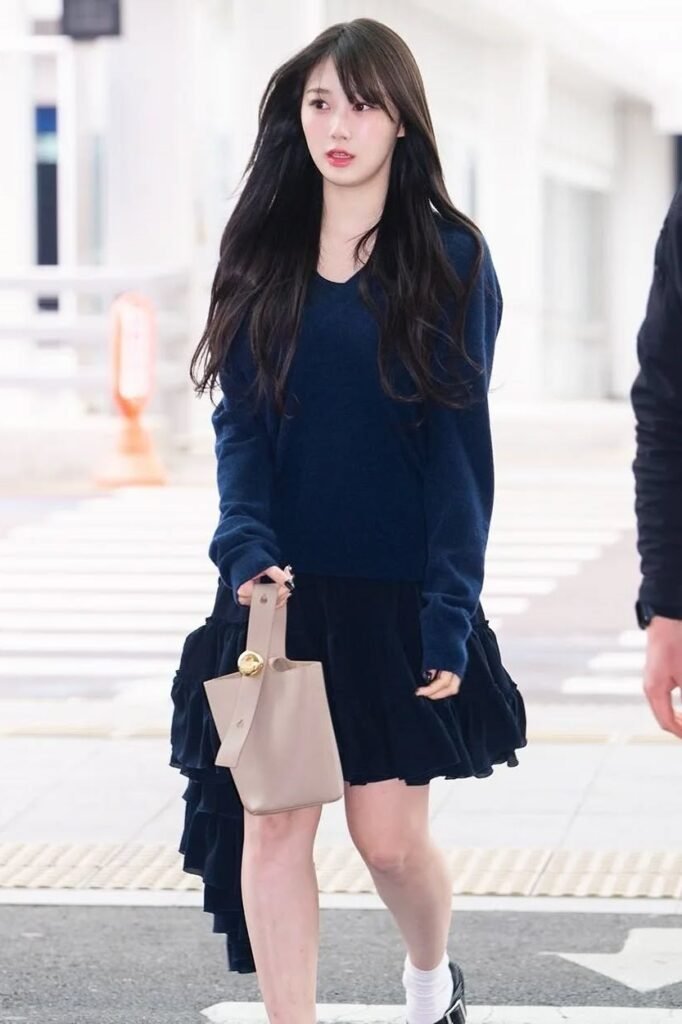 Navy V-Neck Sweater + Black Ruffled Skirt + Beige Bucket Bag