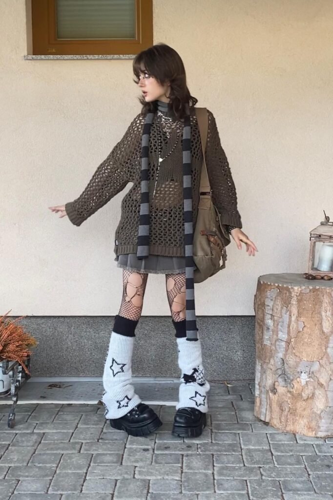 Olive Green Open-Knit Sweater + Grey Pleated Mini Skirt + Star-Patterned Leg Warmers + Chunky Black Shoes