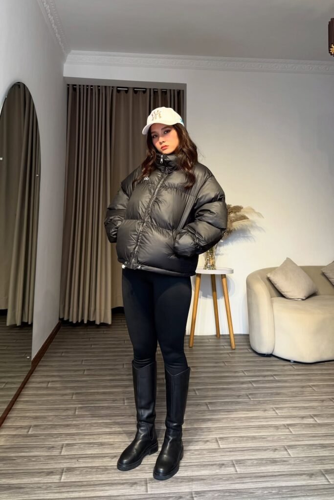 Oversized Black Puffer Jacket + Black Leggings + Knee-High Black Leather Boots + White Baseball Cap