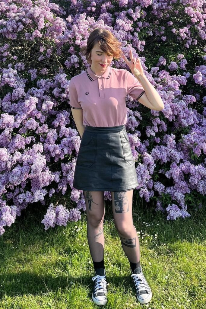Pink Polo Shirt + Black Leather Mini Skirt + Graphic Sheer Tights + Black and White High-Top Sneakers