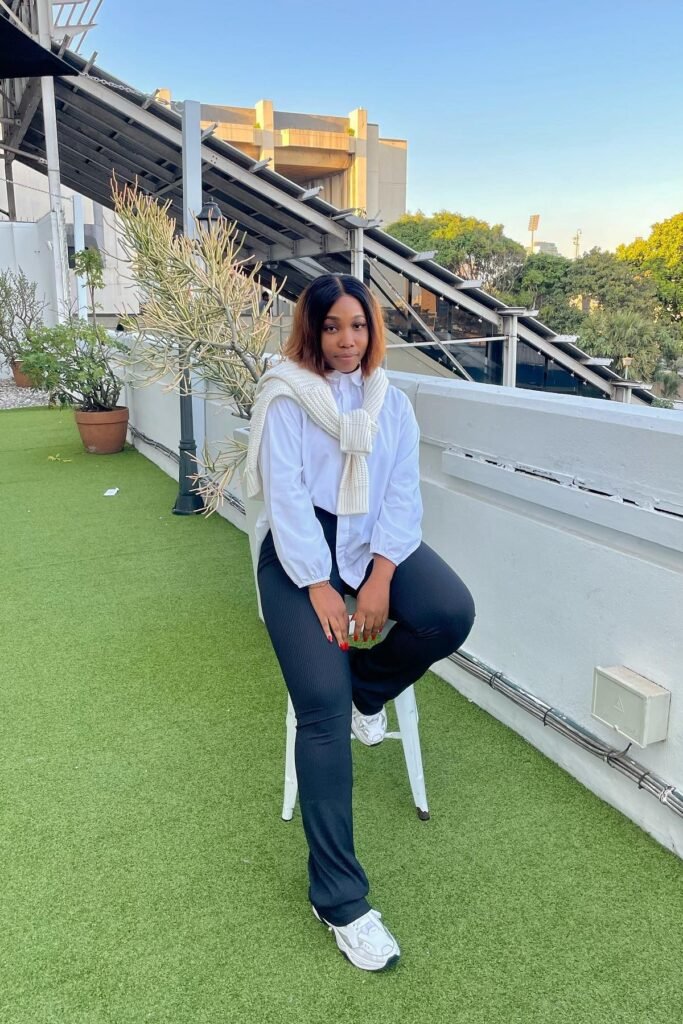 White Button-Down Shirt + Cream Cable-Knit Sweater (shoulders) + Black Ribbed Flared Trousers + White Sneakers