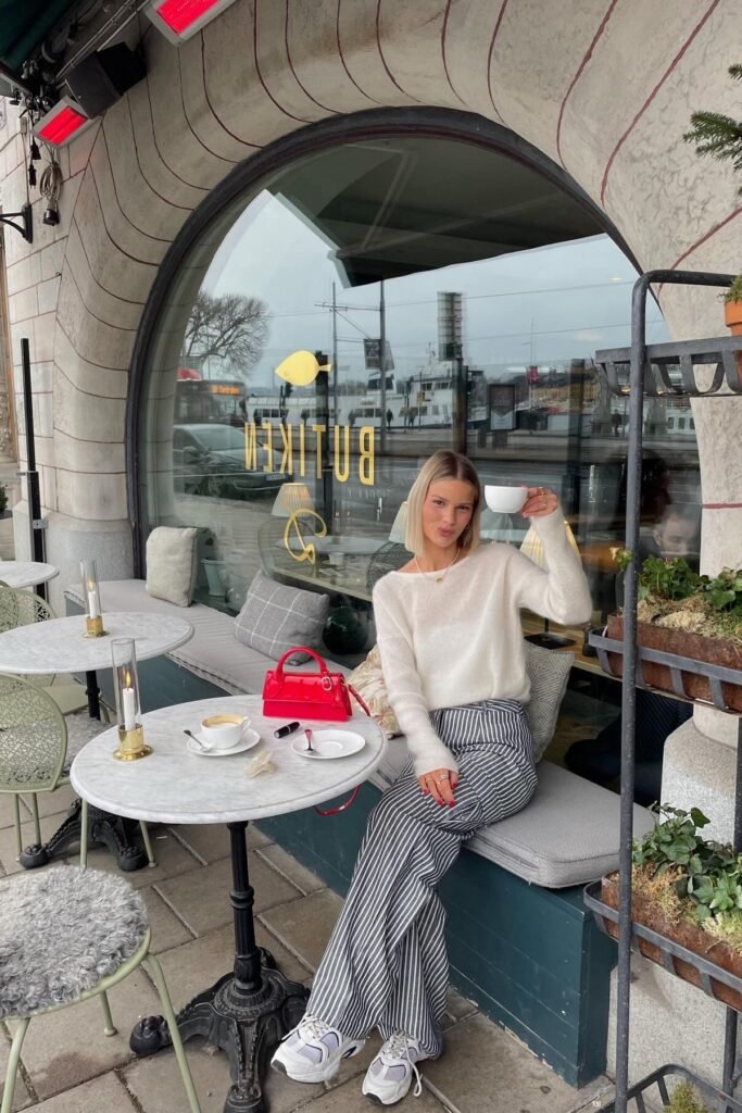 White Sheer Knit Sweater + Grey Pinstripe Wide-Leg Pants + White Athletic Sneakers + Red Patent Handbag