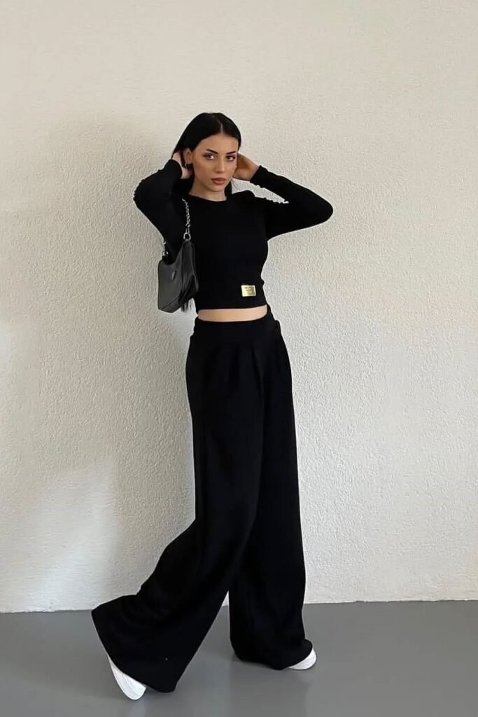 Edgy and cool monochrome brunch outfit: a black long-sleeve crop top with high-waisted wide-leg trousers and white sneakers.