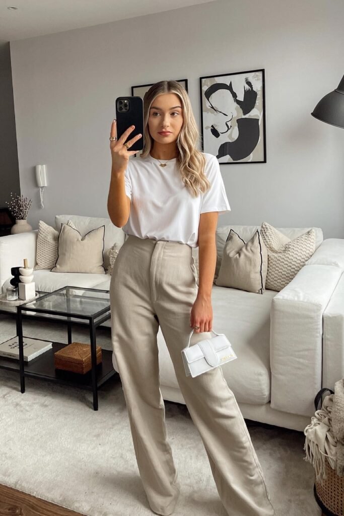 Minimalist and modern brunch outfit: a simple white t-shirt tucked into high-waisted beige wide-leg trousers with a white mini bag.