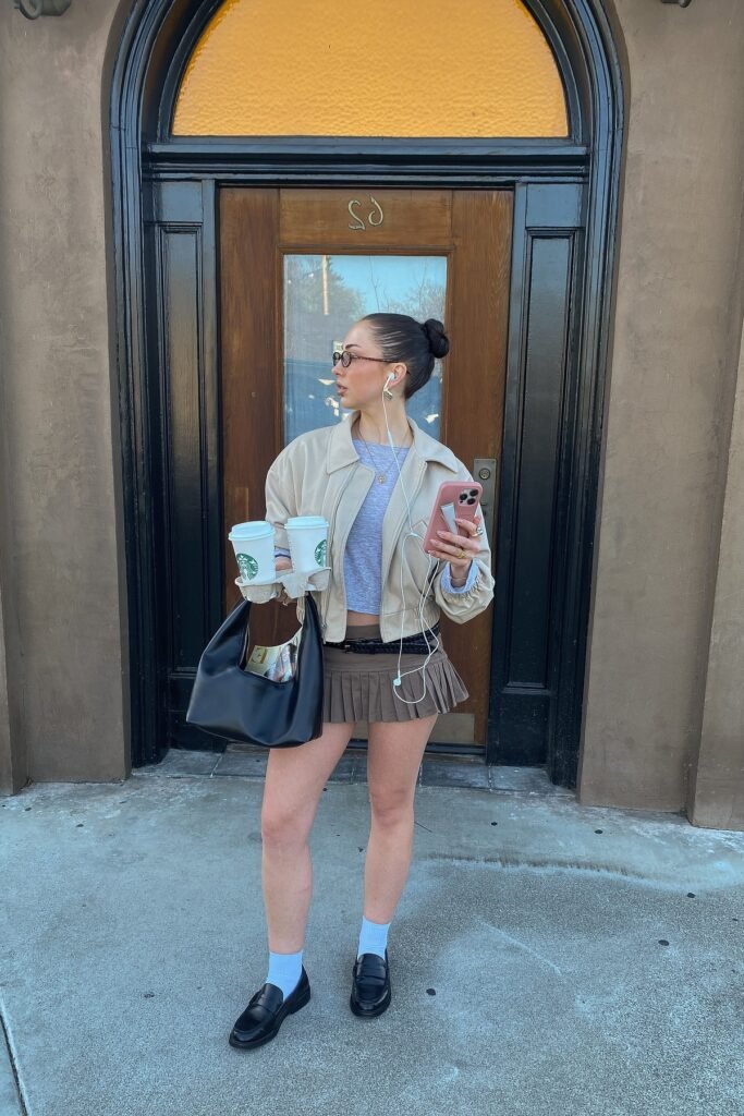 Beige Bomber Jacket + Grey Crop Top + Brown Pleated Mini Skirt + Black Loafers with White Socks