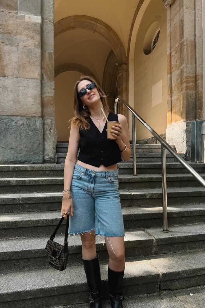 Black Button-Up Vest + Light Wash Raw-Hem Denim Shorts + Black Boots with Hardware