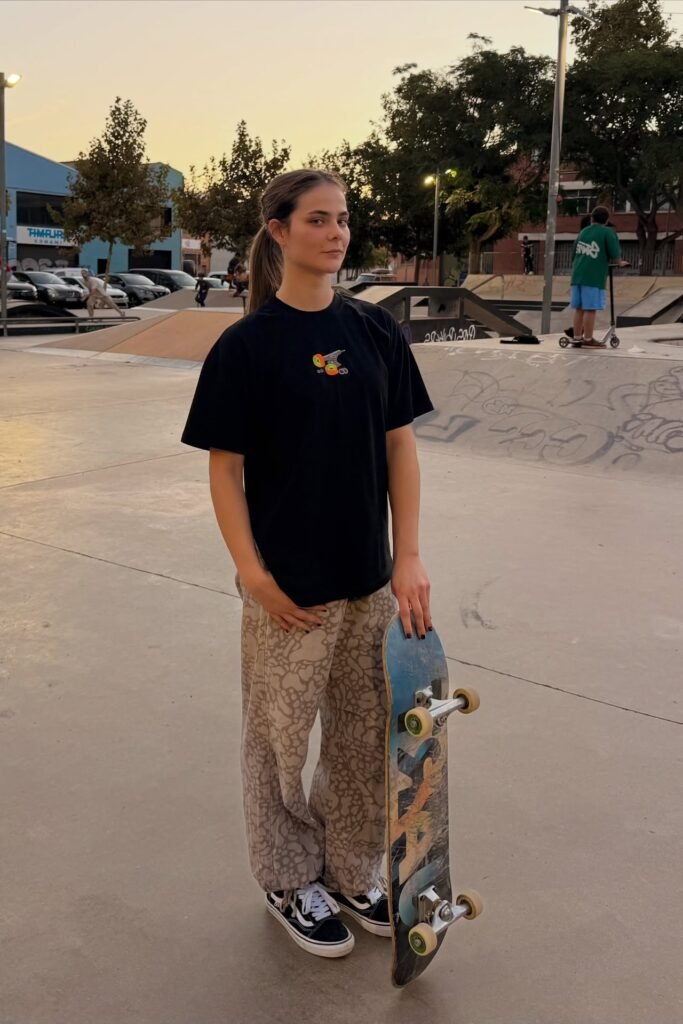 Black Graphic T-Shirt + Beige Patterned Loose Pants + Black & White Old Skool Sneakers