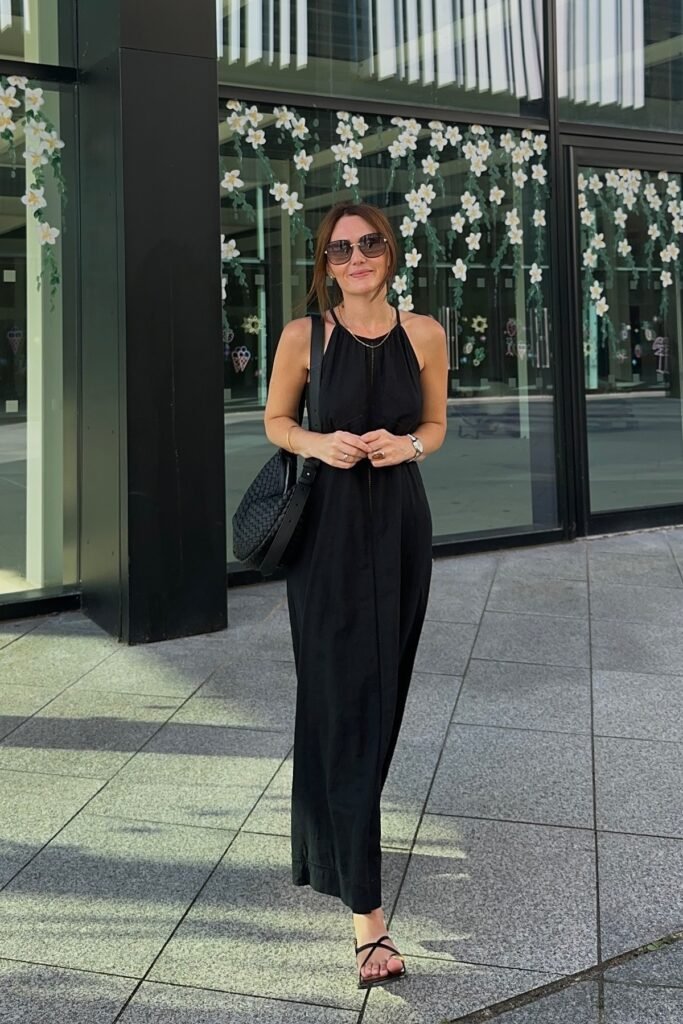 Black Halter-Neck Maxi Dress + Black Strappy Flat Sandals + Black Woven Shoulder Bag