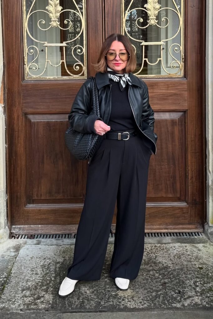 Black Leather Jacket + Black Crewneck Top + Black Pleated Wide-Leg Trousers + White Loafers