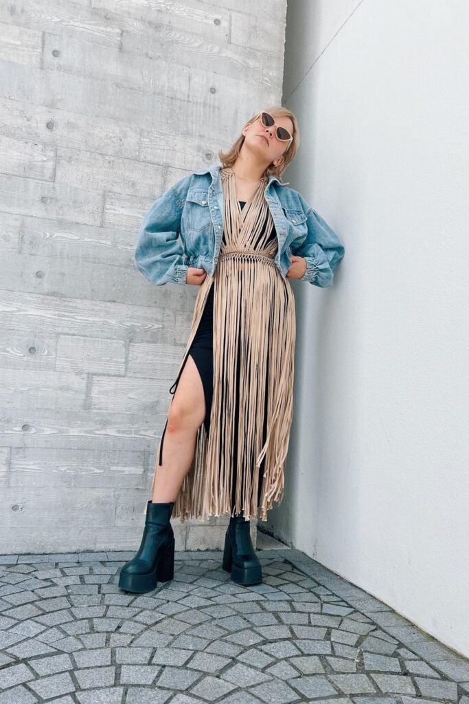 Black Thigh-High Slit Dress + Tan Fringe Overlay + Cropped Denim Jacket + Black Platform Boots