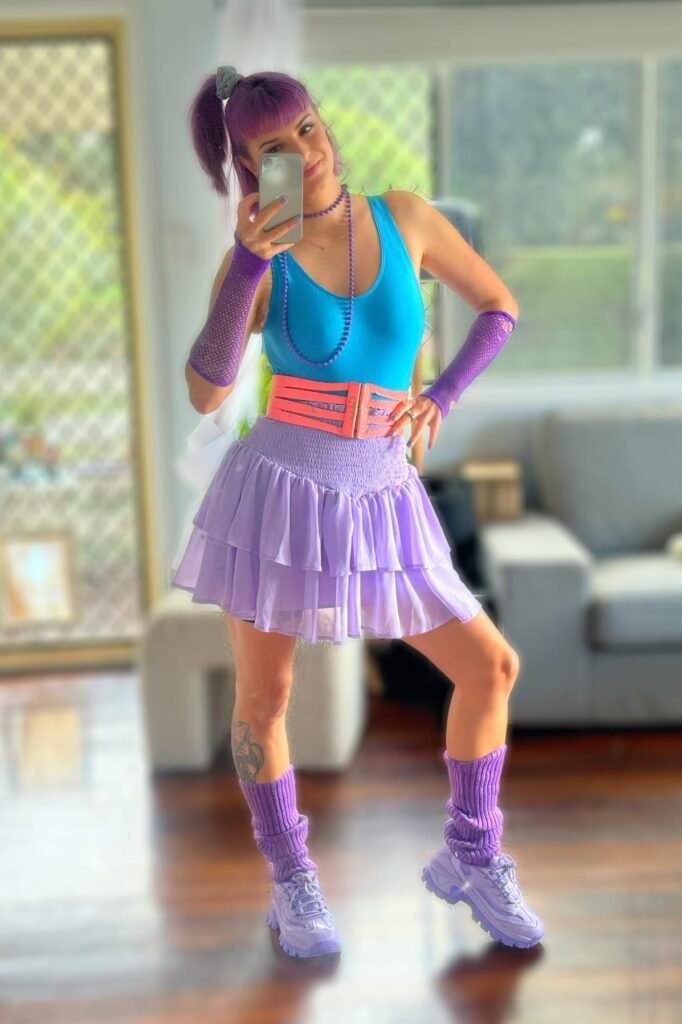 Blue Scoop-Neck Tank Top + Purple Layered Ruffle Skirt + Pink Multi-Strap Belt + Purple Leg Warmers + Purple Sneakers