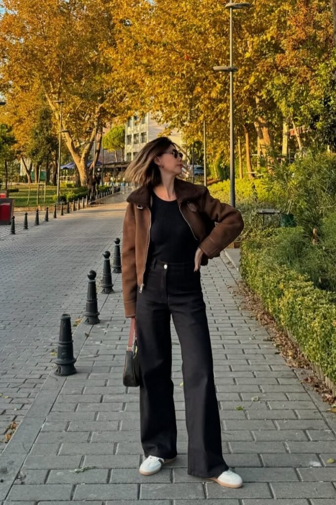 Brown Shearling Aviator Jacket + Black High-Waisted Wide-Leg Jeans + White and Green Retro Sneakers