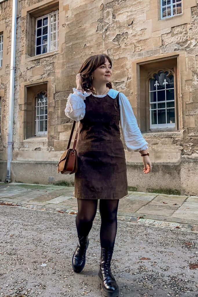 Brown Suede Pinafore Dress + White Puff-Sleeve Blouse + Black Tights + Black Lace-Up Boots