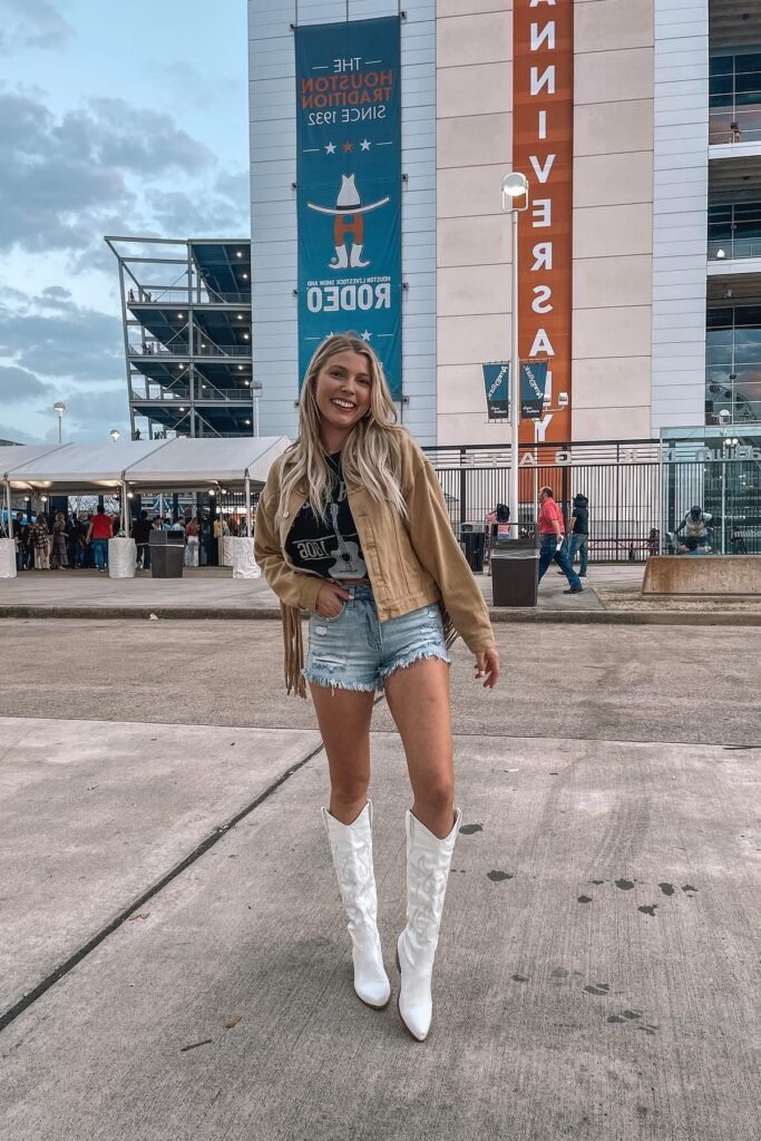 Graphic Crop Top + Frayed Denim Shorts + Tan Fringe Jacket + White Tall Cowboy Boots