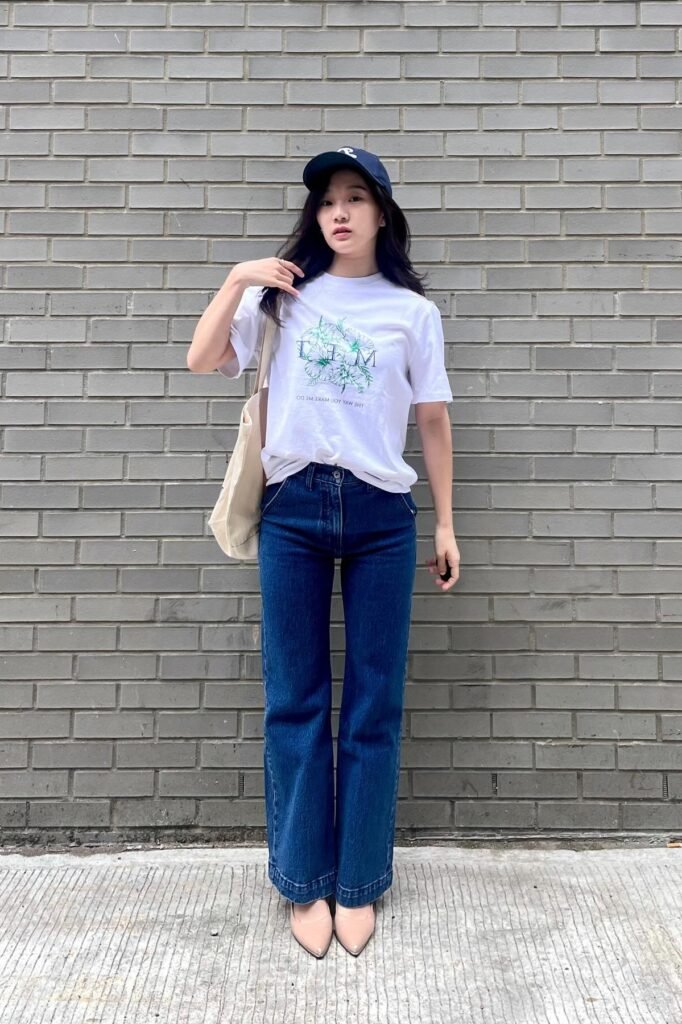Navy Baseball Cap + White Graphic T-Shirt + Wide-Leg Dark Wash Jeans + Nude Pointed Flats