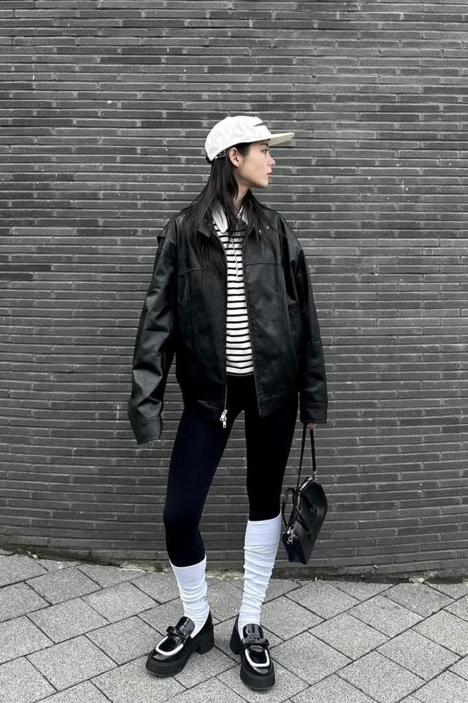 Oversized Black Leather Jacket + Horizontal Striped Shirt + Black Leggings + White Slouch Socks + Black Platform Loafers + White Baseball Cap