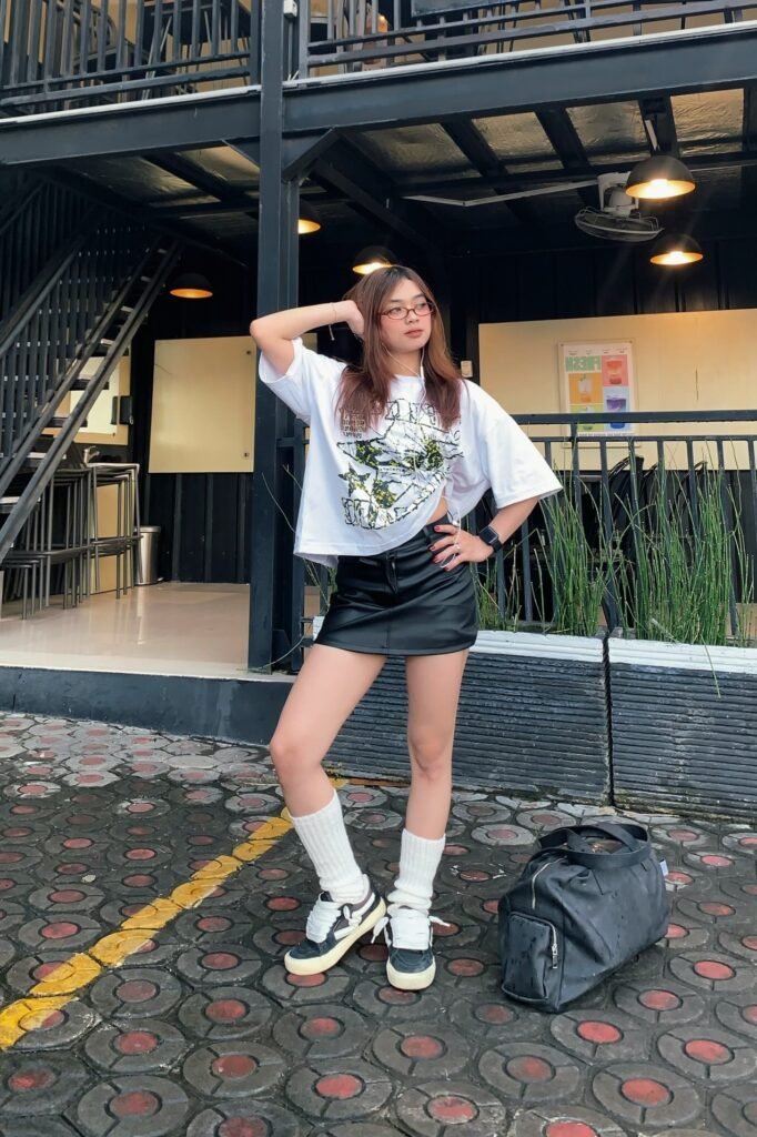 Oversized Graphic T-Shirt + Black Leather Mini Skirt + White Slouchy Socks + Black and White Sneakers