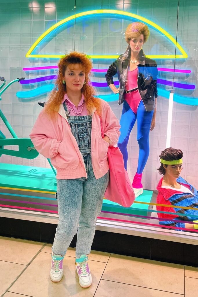 Pink Bomber Jacket + Acid Wash Denim Overalls + Purple and White High-Top Sneakers