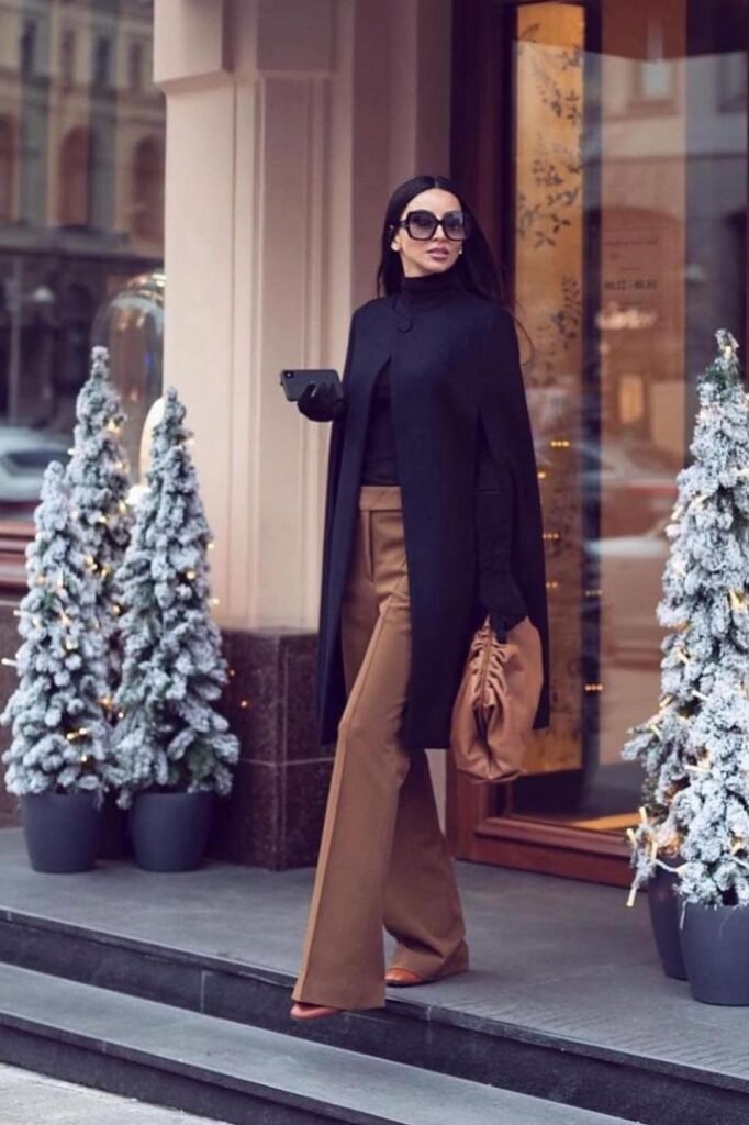 Black Turtleneck + Camel Flared Trousers + Black Cape Coat + Tan Leather Clutch