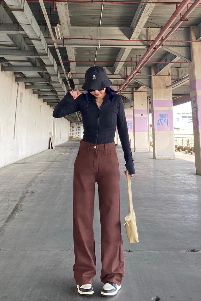 Black Zip-Up Mock Neck Top + Reddish-Brown Wide-Leg Jeans + Black Bucket Hat + Black and White Sneakers