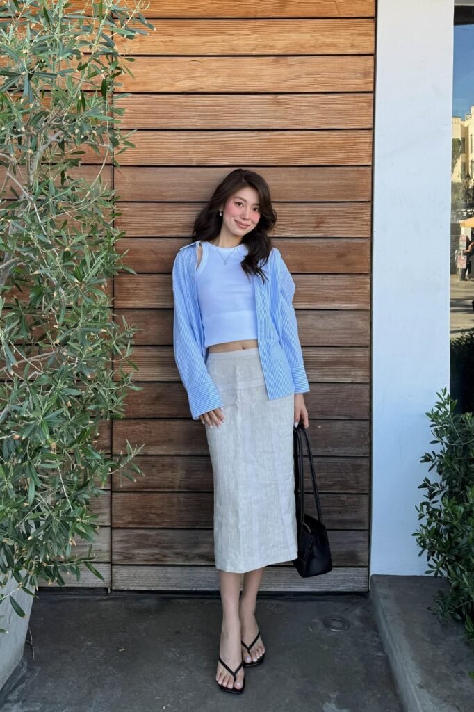Blue and White Striped Button-Down Shirt + White Tank Top + Beige Linen Midi Skirt + Black Strappy Sandals + Black Tote Bag